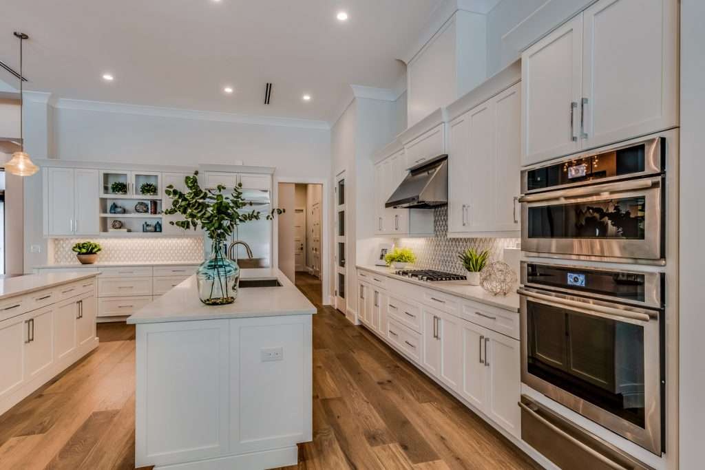 White shaker kitchen with island, wood floors, and stainless double ovens in a Boise hom
